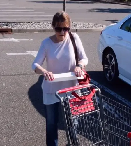 A woman pushing a cart in the street.