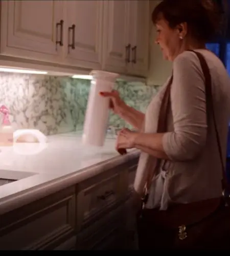 A woman is standing in the kitchen holding something.